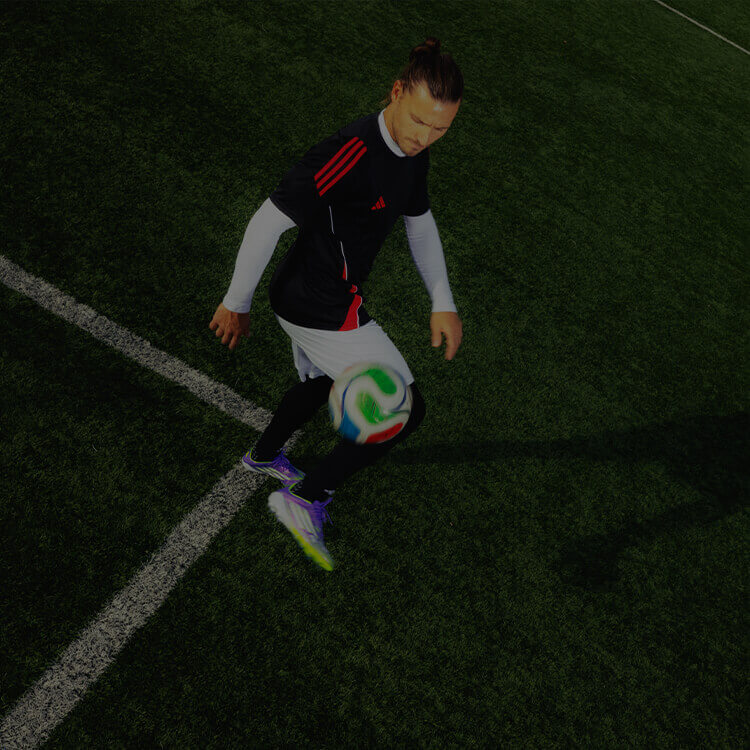 Ragazzo che gioca a calcio vestito con abbigliamento football di adidas